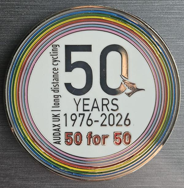 Audax UK 50th anniversary pin displaying &lsquo;50 YEARS 1976–2026&rsquo; in black lettering surrounded by rainbow-coloured rings, with &lsquo;50 for 50&rsquo; text beneath.